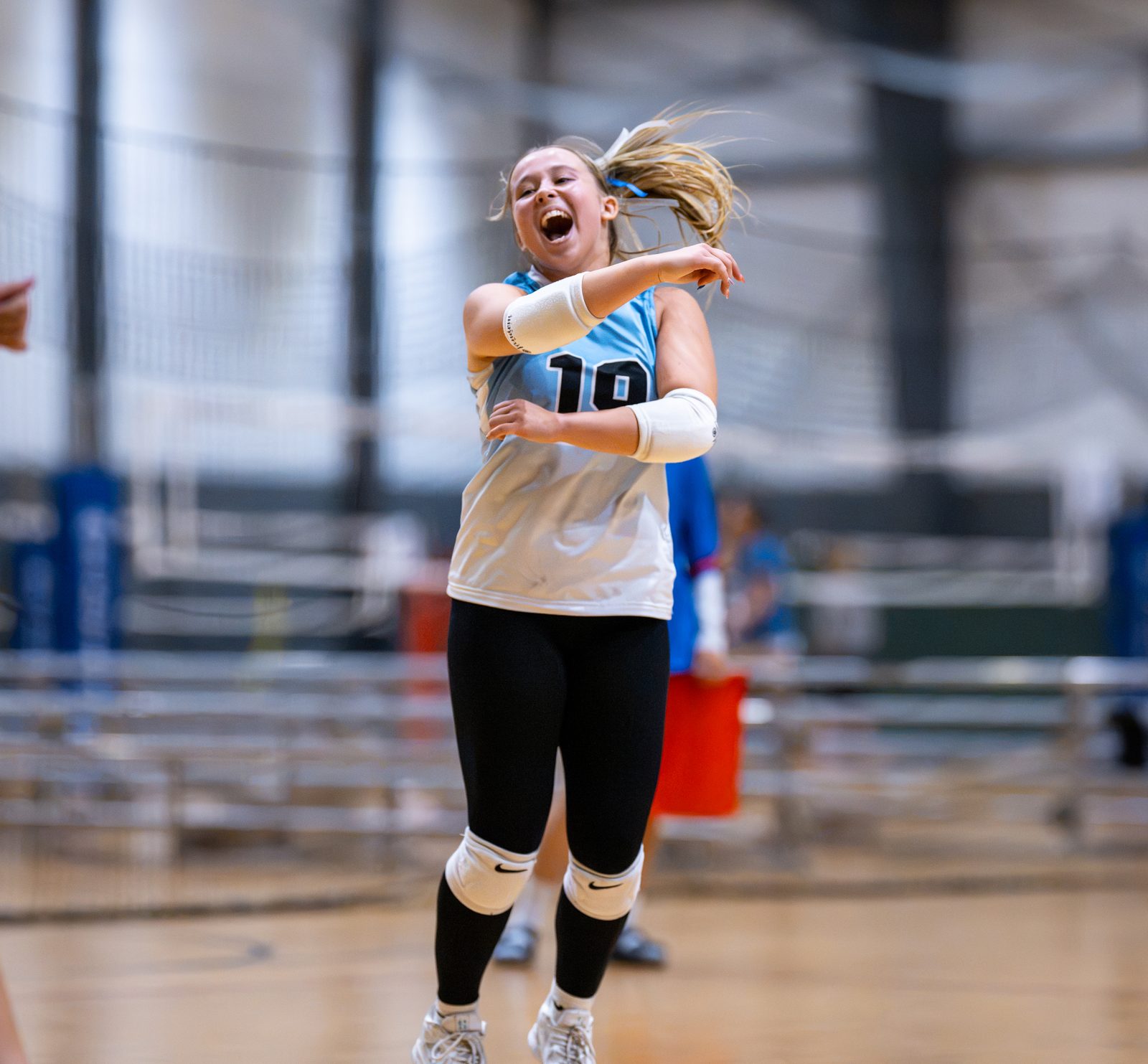 A player in light blue laughs and pumps her fist